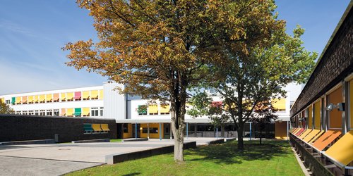 Schulhof Der überdachte Eingangsbereich einer Schule ist mit runden Deckenanbauleuchten ausgestattet.
